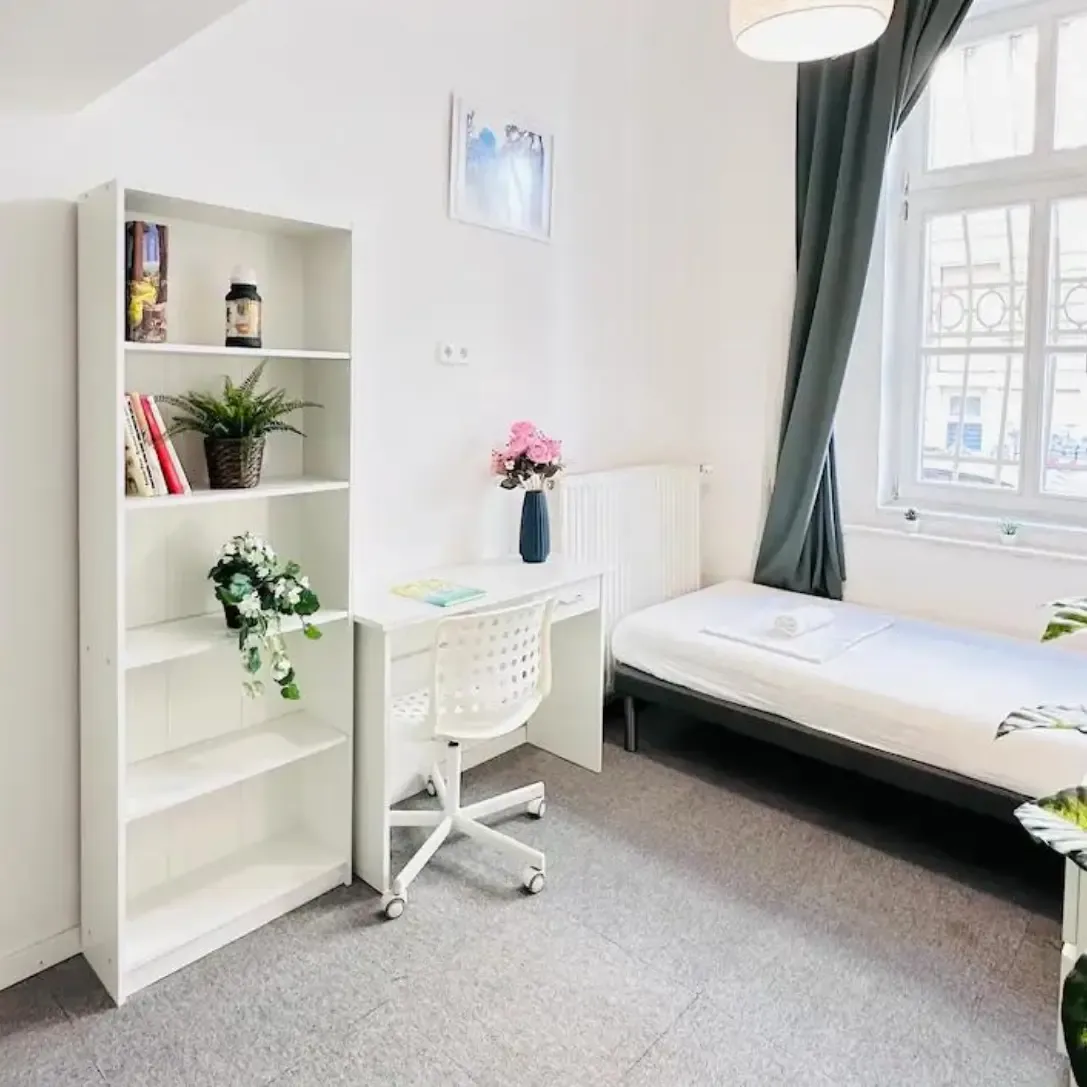 Bright single bedroom with a desk and bookshelf in a Budapest coliving