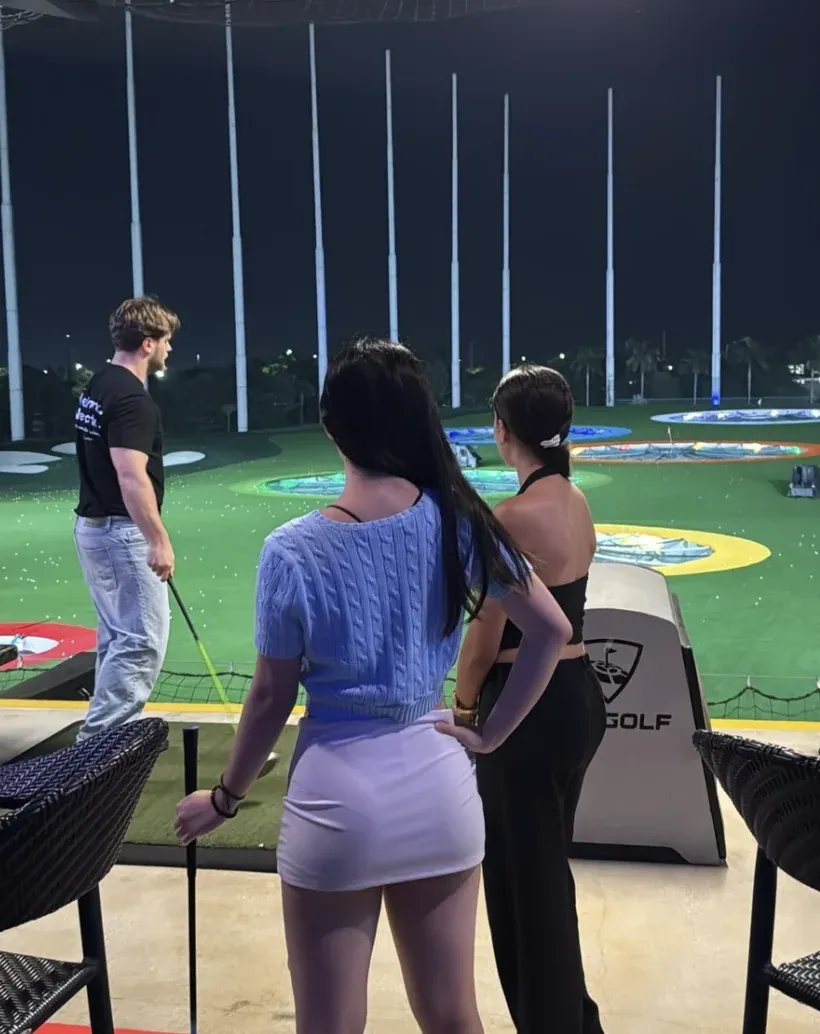 Coliving members playing golf at a night-time driving range in Miami