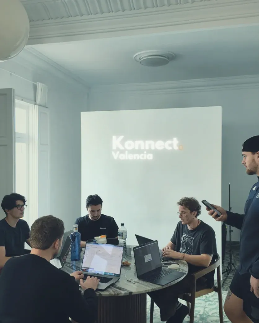 Entrepreneurs working on laptops around a table in a Valencia coliving apartment